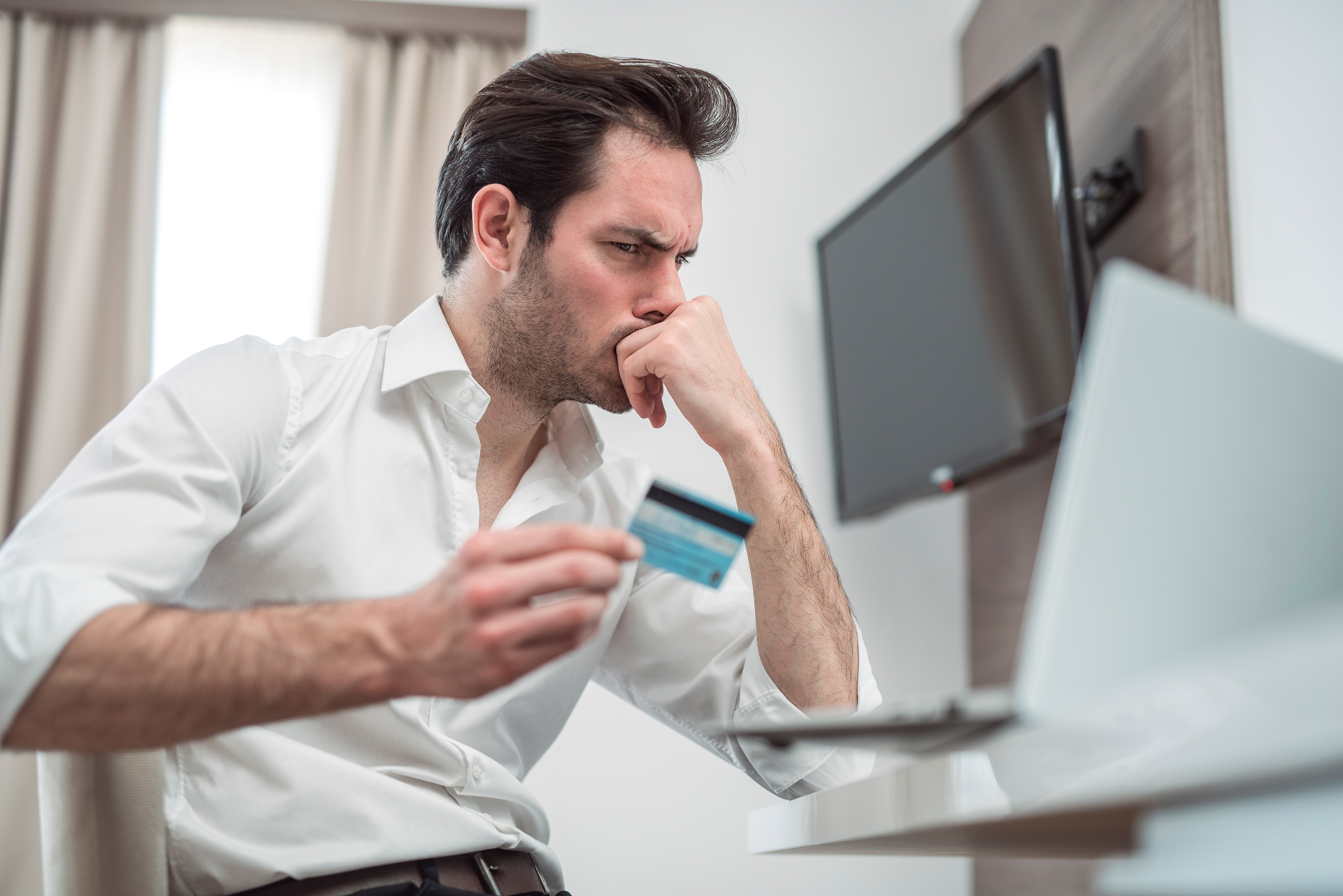 Single business man on the chair in room, looking so sad and worried with credit card and computer